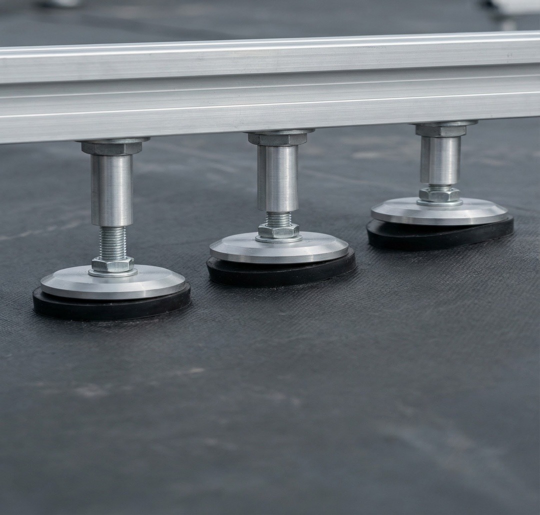 Adjustable BalcoDeck® support pedestals standing on a flat roof, ready to level the deck