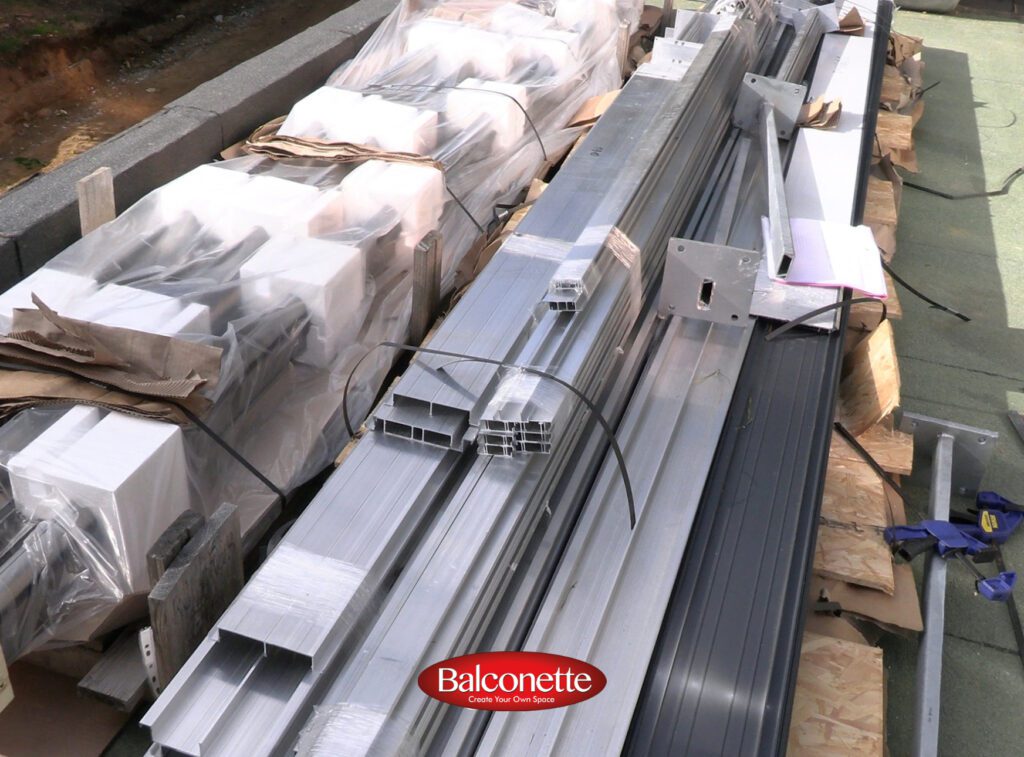BalcoDeck aluminium substructure and decking components stacked on a flat roof ready for installation